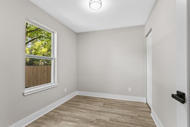 spare room with baseboards, wood finished floors, and a textured ceiling