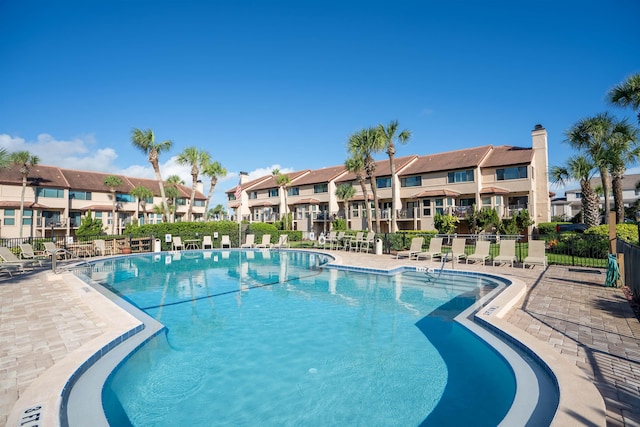 community pool with a patio area, a residential view, and fence