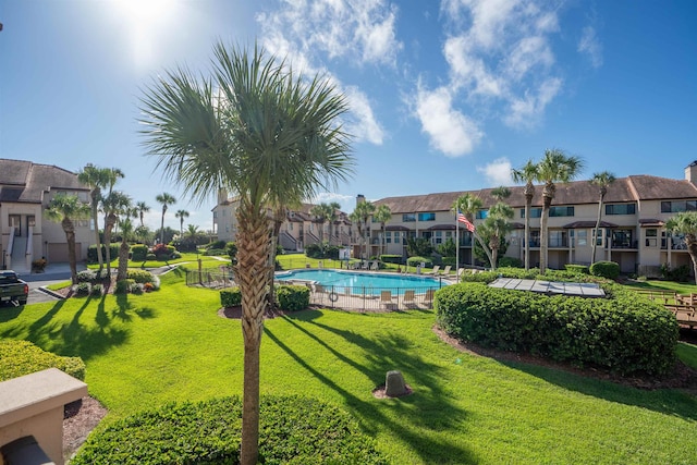 view of property's community with a yard, a swimming pool, and a residential view