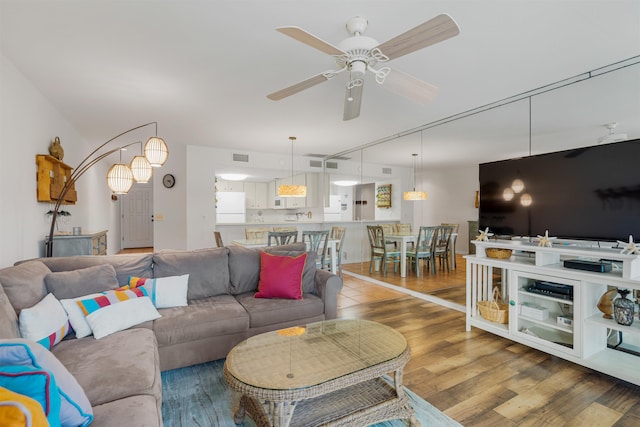 living room featuring visible vents, wood finished floors, and a ceiling fan