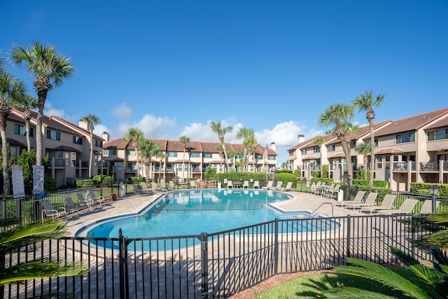 community pool featuring a patio area, a residential view, and fence