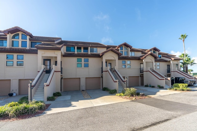 townhome / multi-family property featuring stairs, concrete driveway, an attached garage, and stucco siding