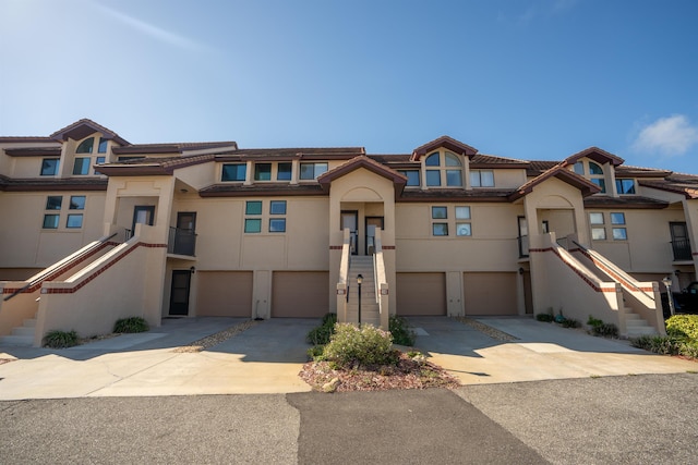 townhome / multi-family property with stairs, concrete driveway, an attached garage, and stucco siding