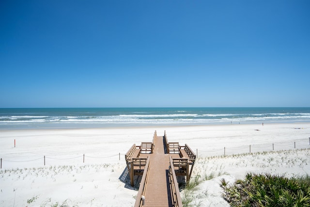 view of home's community with a water view and a beach view