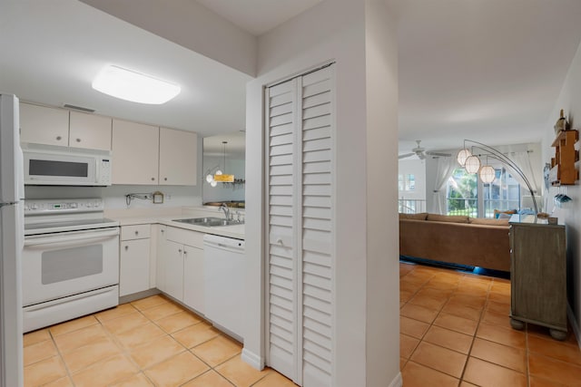 kitchen with light tile patterned floors, light countertops, white appliances, and a sink