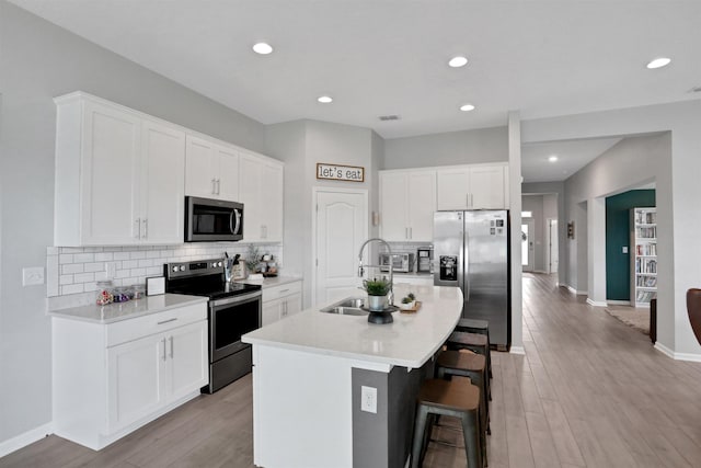 kitchen with sink, a center island with sink, white cabinets, and appliances with stainless steel finishes