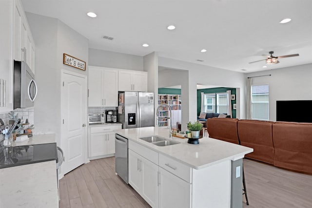 kitchen featuring a center island with sink, white cabinets, sink, decorative backsplash, and stainless steel appliances