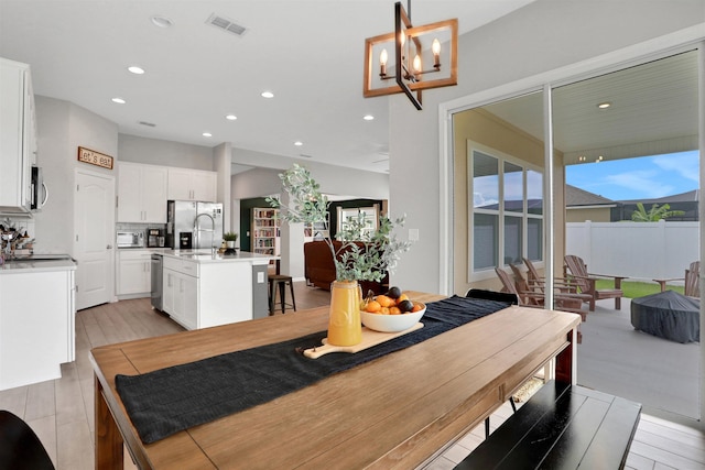 dining room with light hardwood / wood-style floors and an inviting chandelier