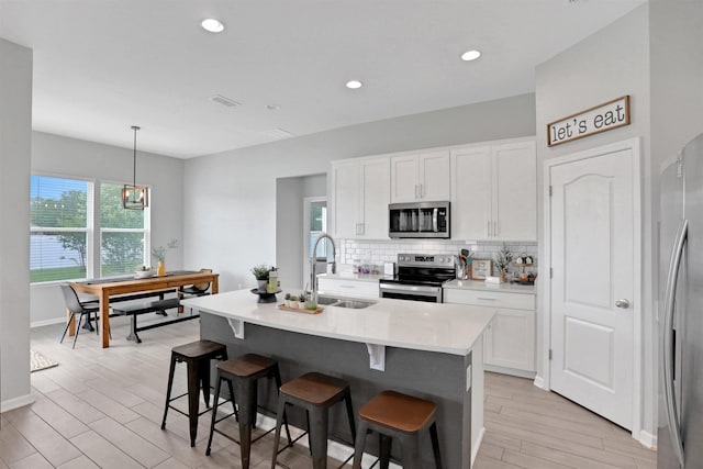 kitchen featuring white cabinetry, sink, pendant lighting, a center island with sink, and appliances with stainless steel finishes