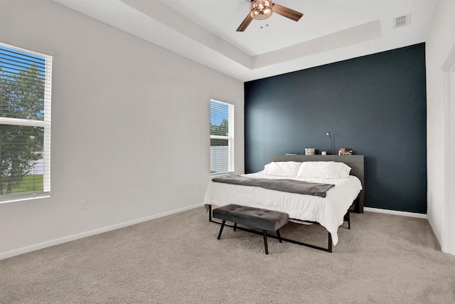 bedroom with ceiling fan, light carpet, and multiple windows