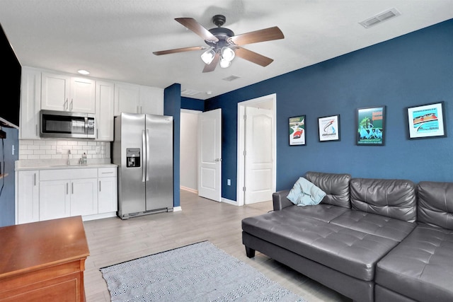 living room featuring ceiling fan, light hardwood / wood-style flooring, and sink