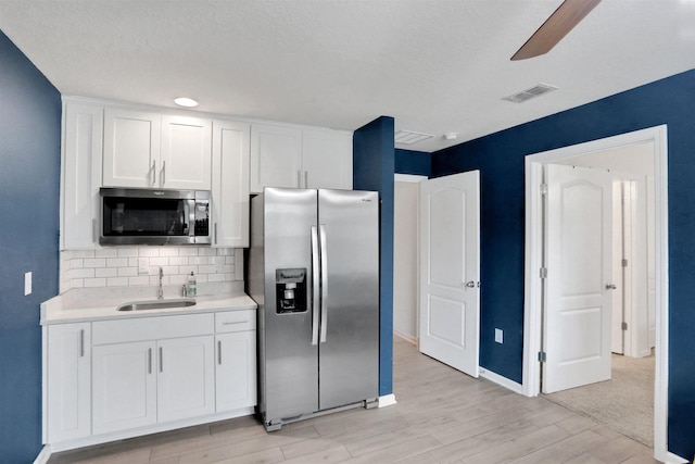 kitchen with white cabinets, stainless steel appliances, light hardwood / wood-style floors, and sink