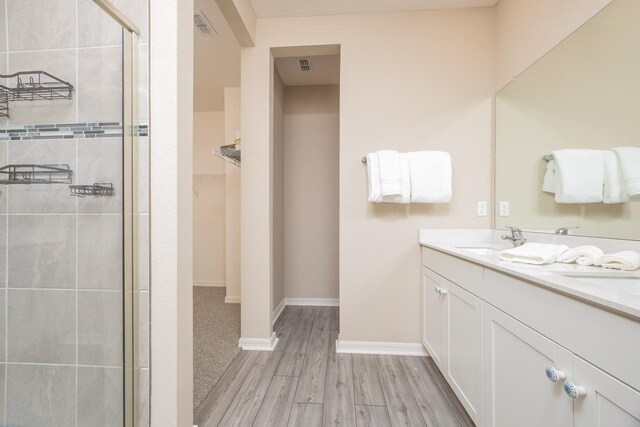 101 Sailors Landing Ct, Saint Augustine, FL 32084 - bathroom featuring a stall shower, a sink, wood finished floors, a spacious closet, and double vanity