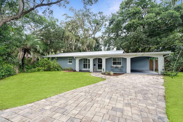 ranch-style home featuring covered porch, a front yard, and a carport