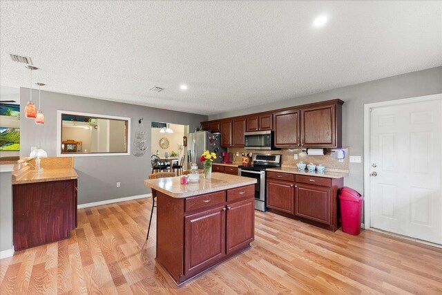 14 Serbian Bellflower Trl, Palm Coast, FL 32164 - kitchen featuring stainless steel appliances, light wood-type flooring, pendant lighting, a breakfast bar area, and a center island