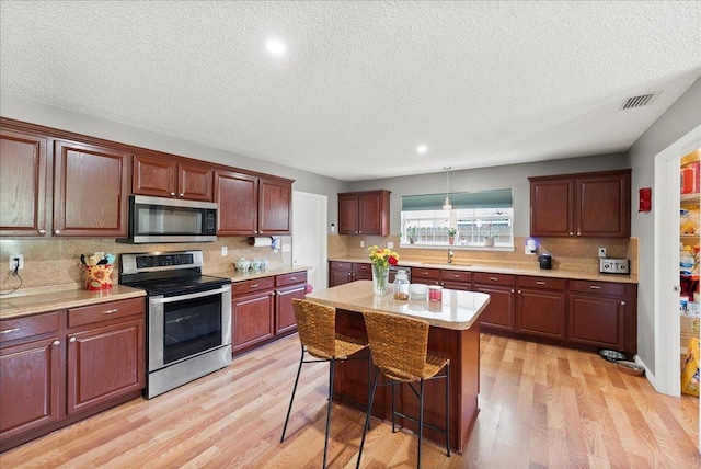 14 Serbian Bellflower Trl, Palm Coast, FL 32164 - kitchen with light countertops, stainless steel appliances, backsplash, light wood-style floors, and visible vents