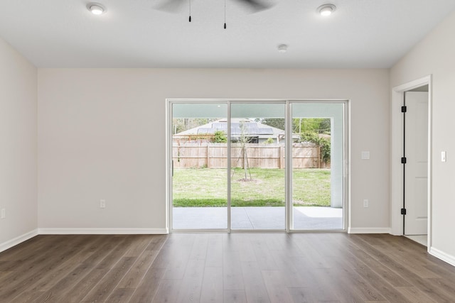 unfurnished room featuring baseboards, dark wood-style flooring, and ceiling fan