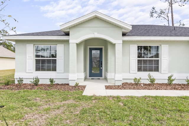 doorway to property with a lawn and roof with shingles