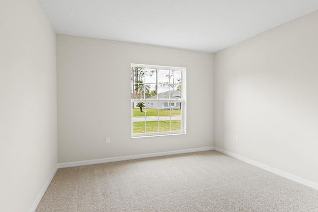 carpeted empty room featuring baseboards