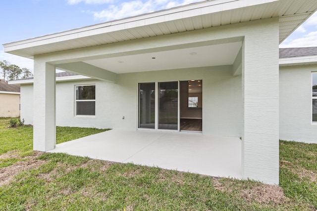 back of property featuring stucco siding, a lawn, and a patio area