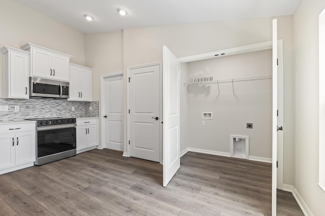 kitchen featuring stainless steel appliances, decorative backsplash, light countertops, white cabinetry, and light wood-type flooring