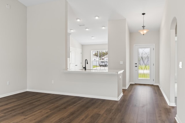 entryway with baseboards, arched walkways, and dark wood finished floors