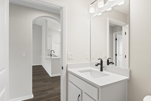 half bathroom with baseboards, wood finished floors, and vanity