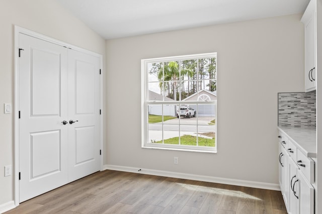 unfurnished bedroom featuring baseboards, light wood-type flooring, and a closet