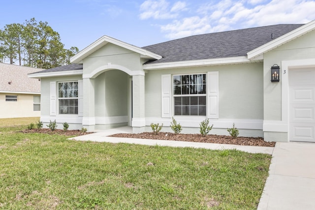 view of front facade featuring a front yard, a garage, and a shingled roof