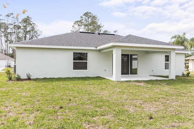 back of property featuring roof with shingles, stucco siding, a yard, a garage, and a patio