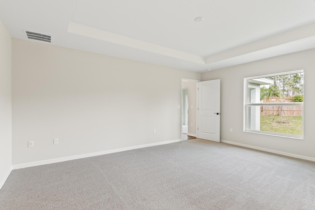 empty room with a raised ceiling, baseboards, and visible vents