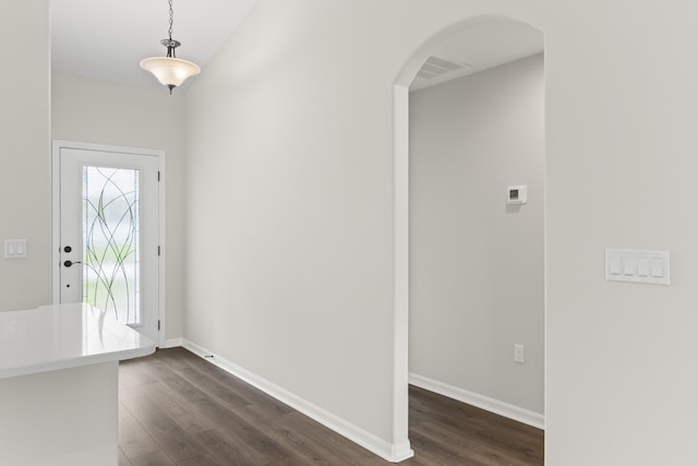 foyer entrance featuring visible vents, arched walkways, dark wood-style flooring, and baseboards