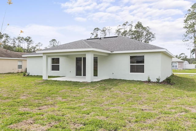 back of house with stucco siding, a lawn, roof with shingles, and a patio area