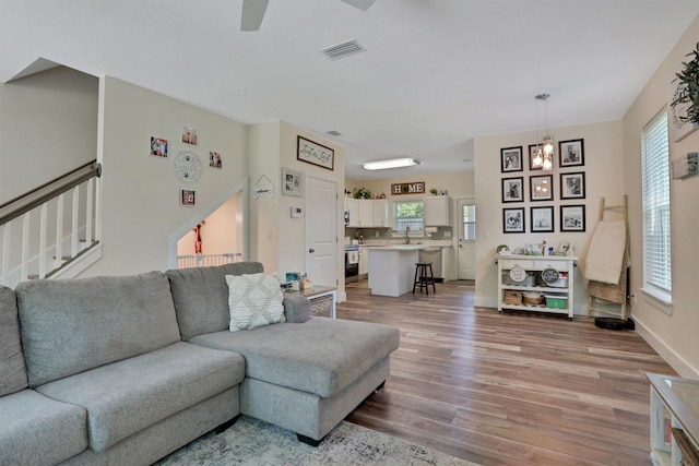 living room with light hardwood / wood-style flooring and ceiling fan with notable chandelier