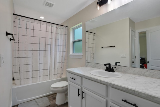 full bathroom featuring hardwood / wood-style floors, vanity, shower / bath combination with curtain, and toilet