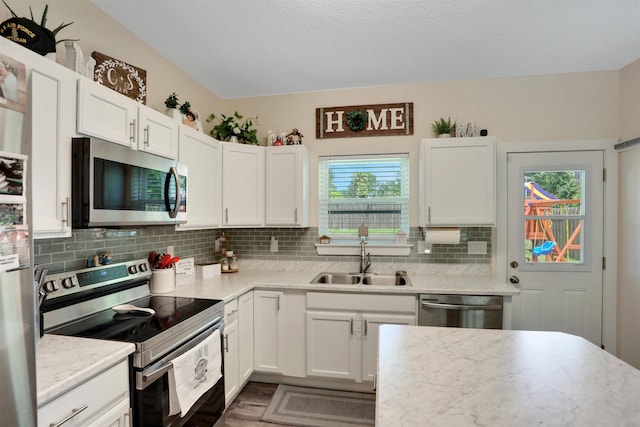 1312 Eisenhower Dr, Saint Augustine, FL 32084 - kitchen featuring stainless steel appliances, decorative backsplash, and white cabinetry