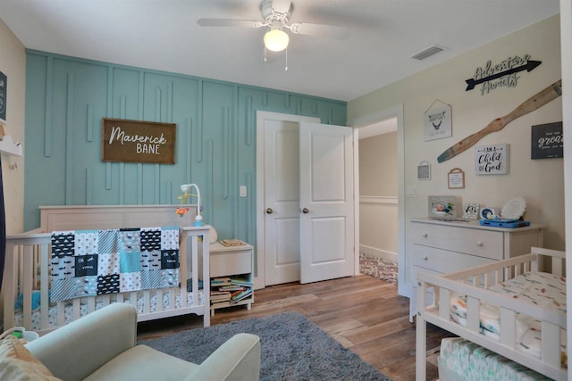 bedroom featuring a crib, light wood-type flooring, and ceiling fan