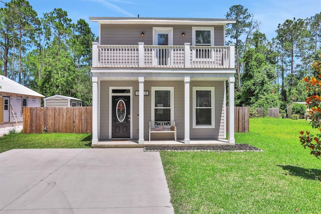 view of front of home featuring covered porch, a balcony, and a front lawn