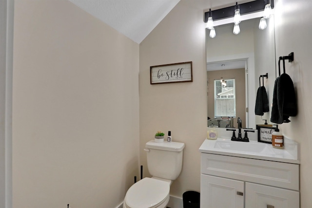 bathroom featuring vanity, toilet, and lofted ceiling