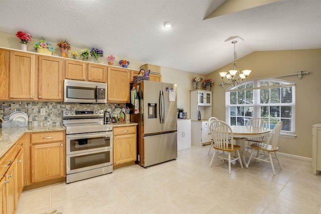 kitchen featuring lofted ceiling, pendant lighting, appliances with stainless steel finishes, light stone countertops, and decorative backsplash