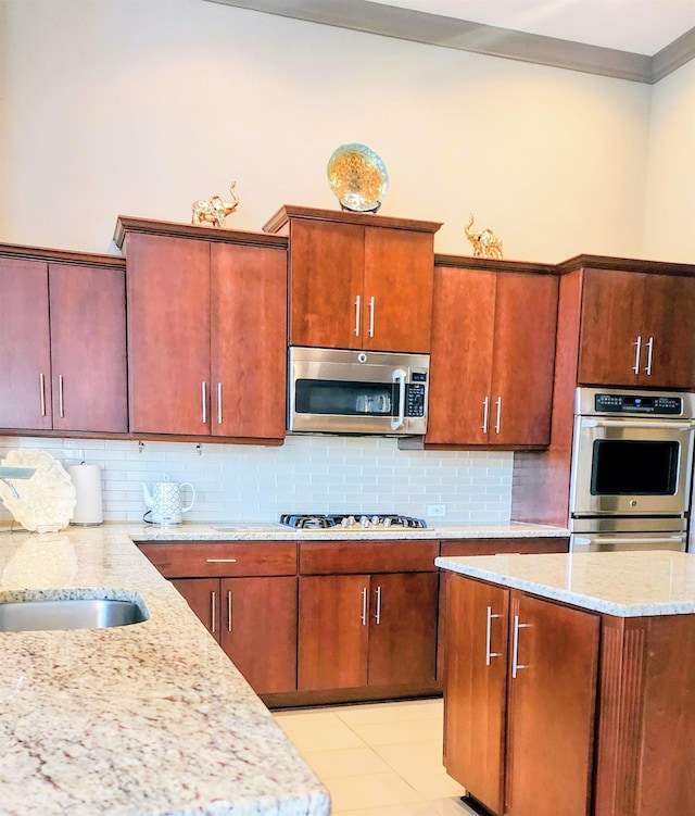 kitchen featuring gas cooktop, backsplash, light stone counters, and light tile patterned flooring