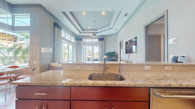 kitchen with dishwasher, sink, ornamental molding, a tray ceiling, and light stone countertops