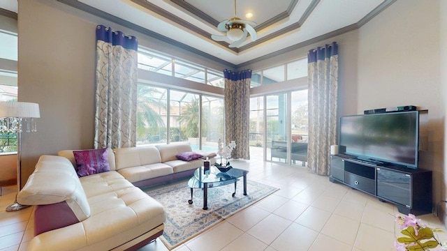 living room with a high ceiling, ornamental molding, light tile patterned floors, and a tray ceiling