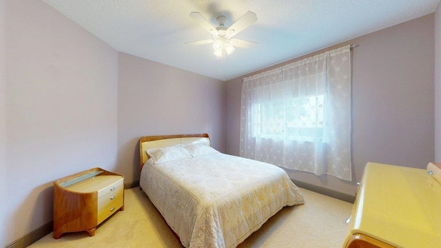 carpeted bedroom featuring ceiling fan and a textured ceiling