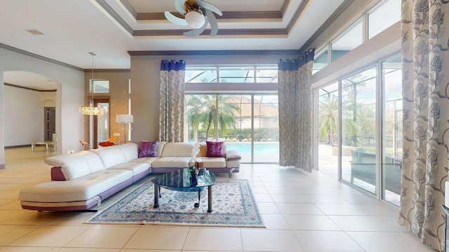 tiled living room with crown molding, a wealth of natural light, ceiling fan, and a tray ceiling