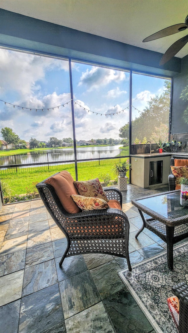 sunroom / solarium featuring a water view, ceiling fan, and sink