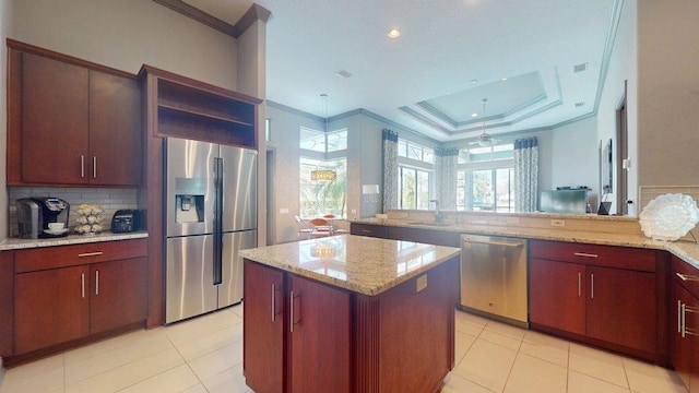 kitchen featuring appliances with stainless steel finishes, sink, a center island, light stone counters, and a raised ceiling