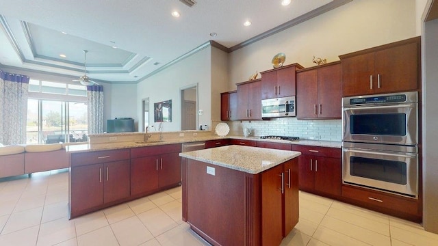 kitchen featuring a kitchen island, appliances with stainless steel finishes, kitchen peninsula, sink, and a tray ceiling