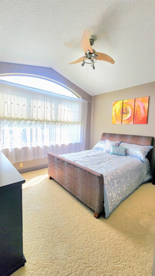 bedroom featuring carpet flooring, a textured ceiling, ceiling fan, and lofted ceiling