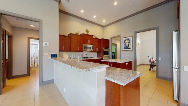 kitchen with a center island, stainless steel appliances, kitchen peninsula, and light stone countertops